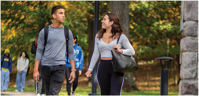 Berkeley College students walk and talk together on a tree-lined path in at the Woodland Park campus. 