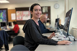 A Berkeley College student wearing black medical scrubs and a stethoscope around their neck is smiling in a clinical setting.