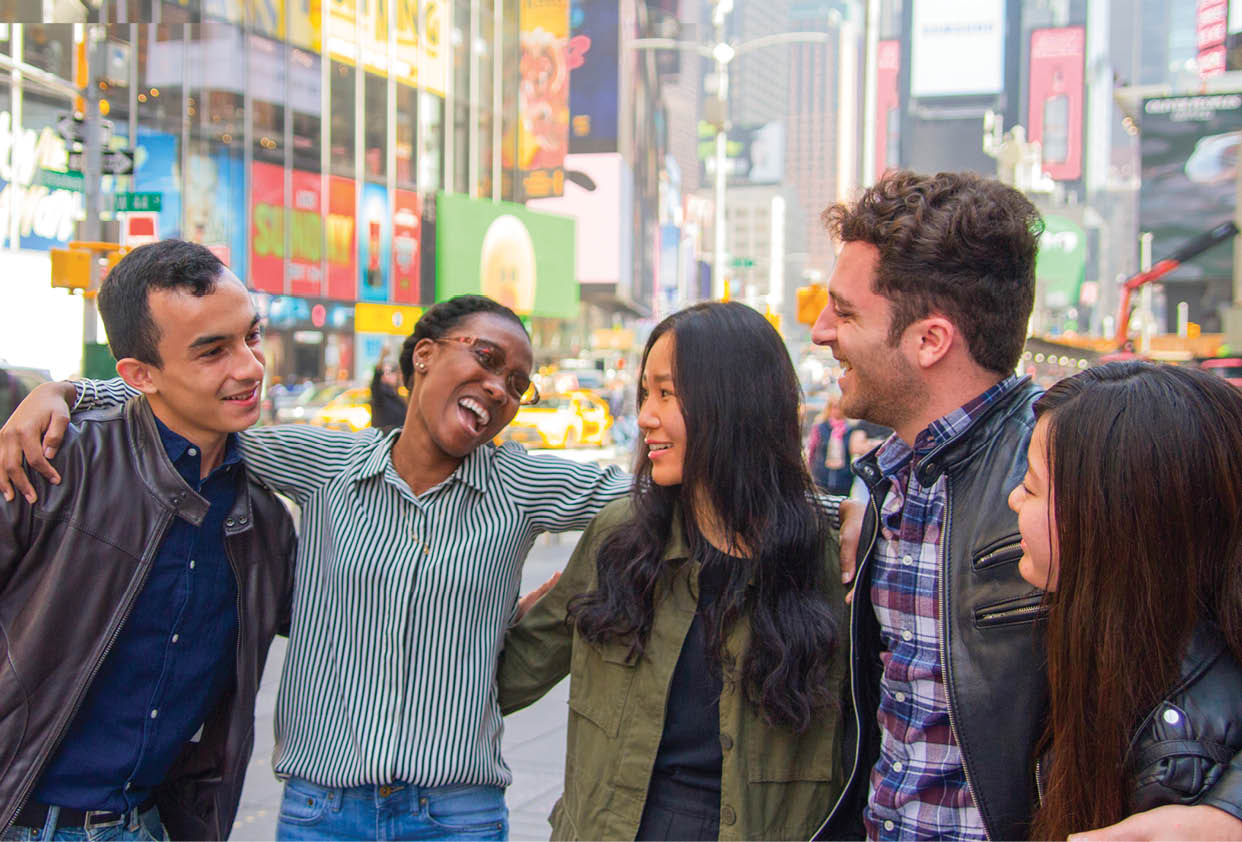 Five Berkeley College students with casual clothing are standing close together Times Square New York City, smiling and engaging happily with each other. 